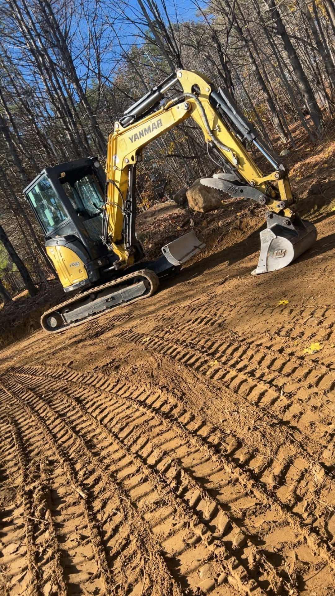 Mini excavator grading a sloped site in Central Maine