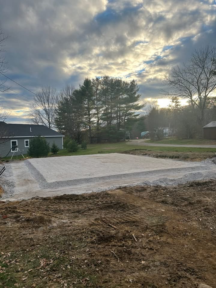 Finished compacted gravel pad built beside a Maine home at sunset