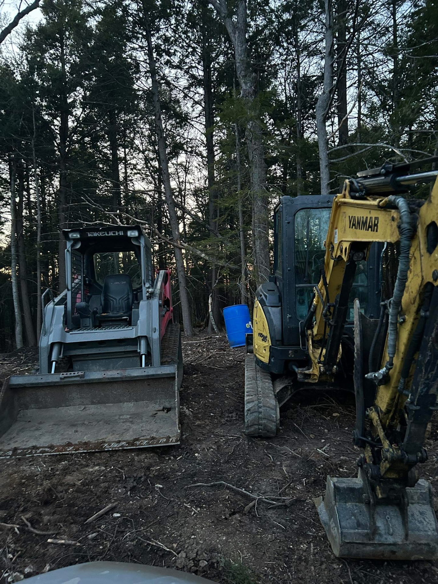 Track loader and mini excavator working on a wooded lot clearing job