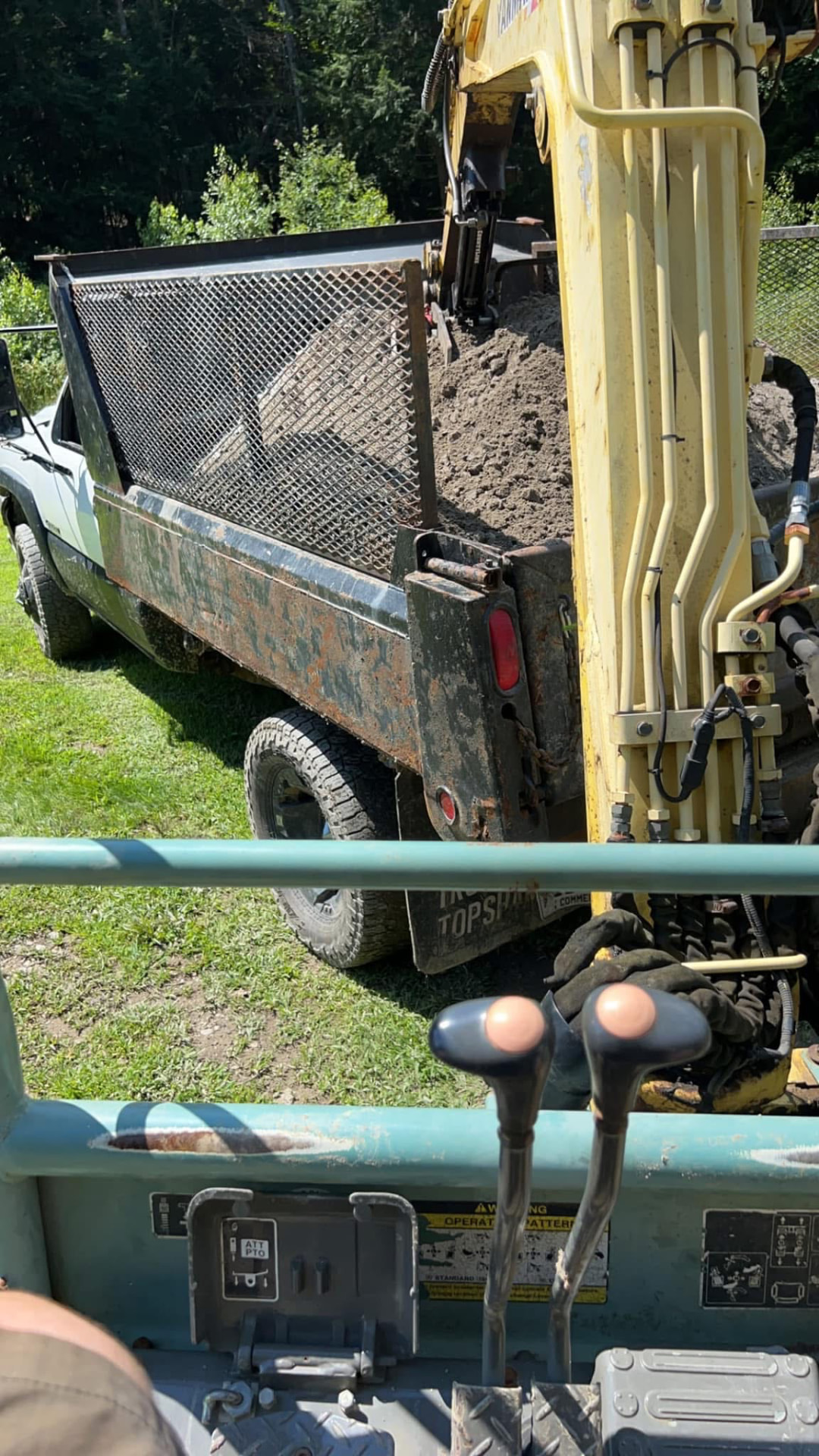 Excavator loading soil into a dump truck on a residential property