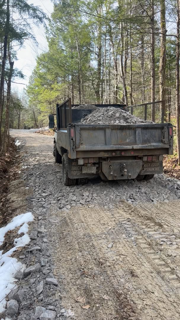 Dump truck loaded with crushed stone on a wooded gravel road