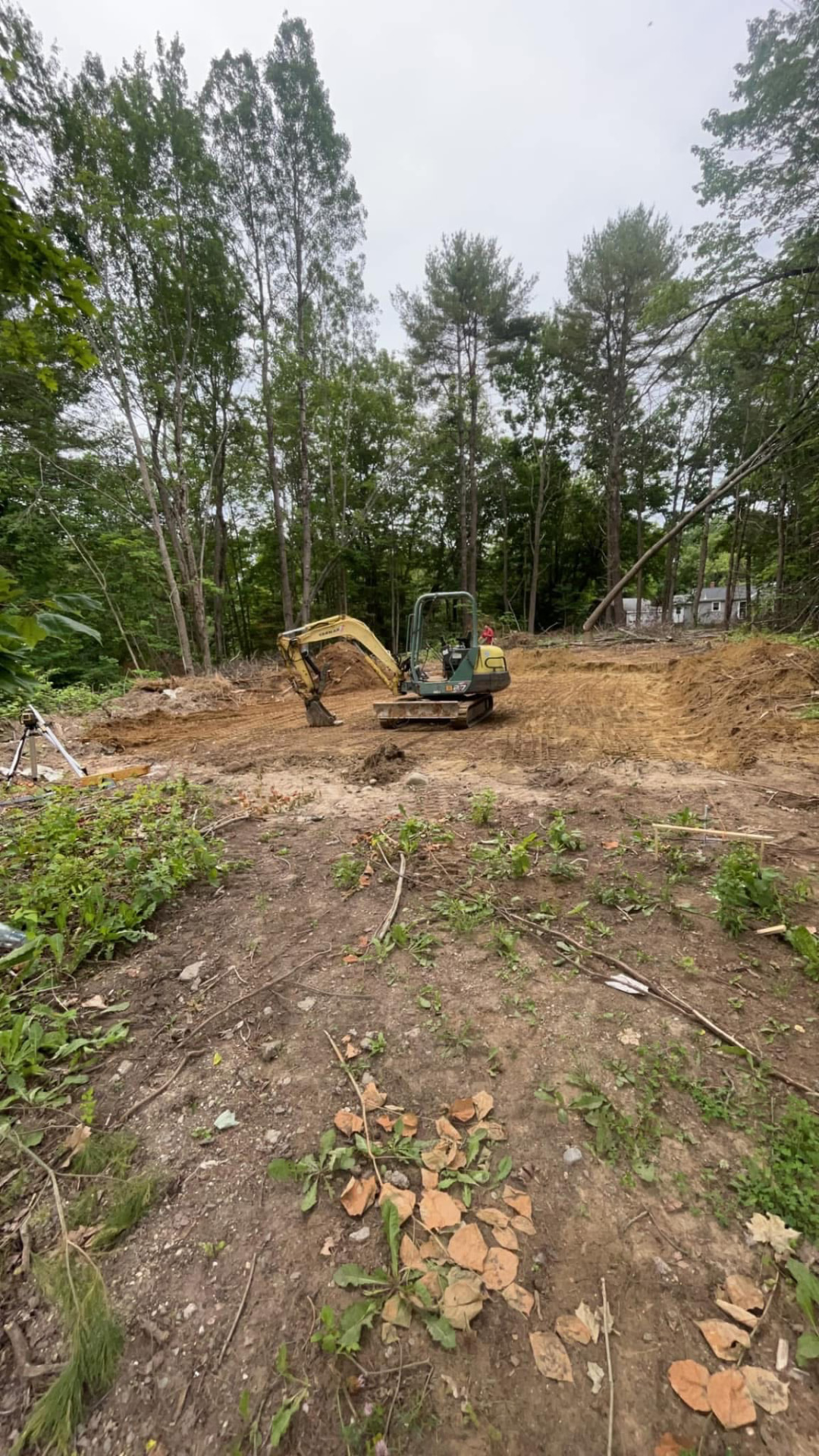 Mini excavator grading a cleared house lot in Central Maine