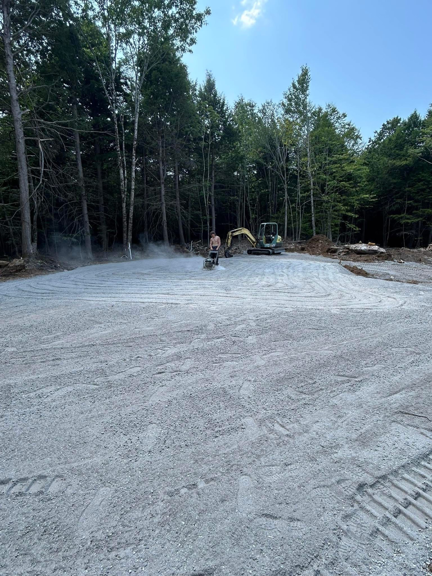 Freshly compacted gravel pad being finished with a plate compactor
